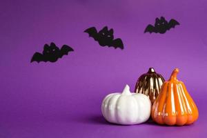 Halloween backgrounds of white, orange and gold pumpkins, spiders and black bats on a purple background with cobwebs and terrible scenery. Horror and a scary holiday with copy space photo