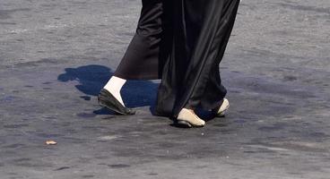 Close up of woman's feet walking. Woman in long skirt and black shoes walking photo