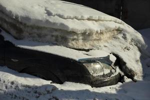 Car under snow. In winter in parking lot. Transport after snowfall. Machine under infusion of ice. photo