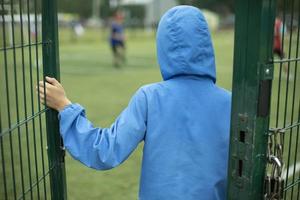 Door to stadium. Child holds grille. Boy walks into schoolyard. photo