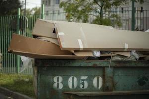 Cardboard in dumpster. Garbage can outside. Discarded cardboard. photo