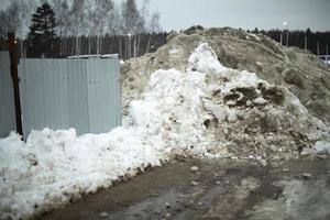 la valla está cubierta de nieve. quitado la nieve al lado de la carretera. foto