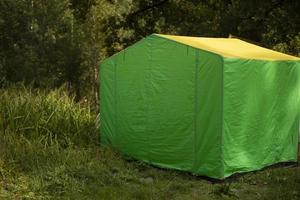 Green tent in forest. Tent for trade in park. Green awning in nature. photo