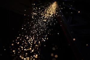 Sparks in dark. Stream of lights on black background. Metal crushing. High temperature. photo