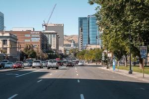 Cars moving on road amidst modern buildings in city during sunny day photo