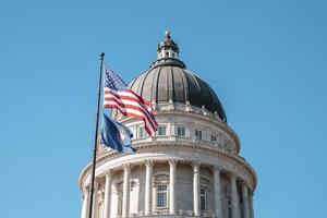 American flag waving at State Capitol Building with blue sky in background photo