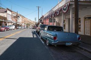 Various cars parked in row on roadside amidst old stores at city on sunny day photo