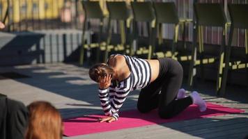 Woman stretches on yoga mat on an outdoor deck video