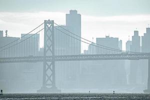 View of Bay Bridge and urban skyline in city during foggy weather photo
