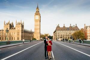 Beautiful city and people. Young family couple stand on Westminster bridge in background with Big Ben, enjoy free time together in London, have good relationships. City landscape background. photo