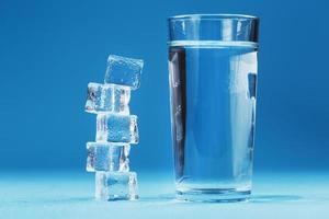 A glass of ice and clear water, ice cubes on a blue background. photo