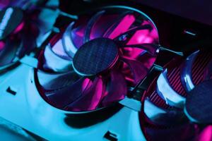 Gaming graphics card with neon magenta-cyan illumination and high-speed fans. photo