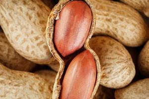 Peanut fruit peeled against the background of unpeeled peanuts. photo