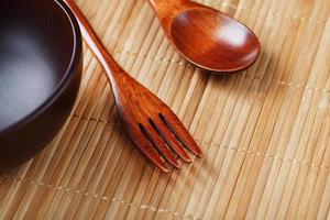 plato, cuchara y tenedor de madera natural sobre base de bambú. foto