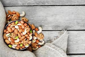 Assorted nuts in a plate on a wooden table with a burlap cloth. photo