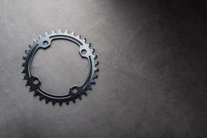 A black bicycle driving star with contrasting repeating cogs on a dark background photo