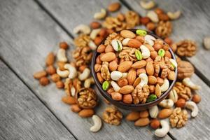 Assorted nuts in a plate on a wooden table with a burlap cloth. photo