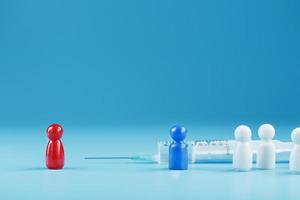 A syringe with a vaccine in the center with a blue and red man with a crowd of whites on a blue background. photo