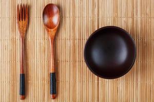Natural wood plate, spoon and fork on a bamboo backing. photo