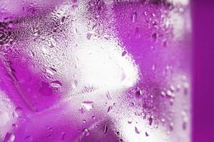 Ice cubes in a glass with refreshing ice water on a pink background. photo