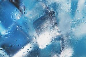 Ice cubes in a glass with refreshing ice water on a blue background. photo