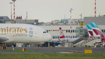 dusseldorf, alemania 23 de julio de 2017 - llegó un enorme airbus a380 de emirates airlines, rodando hasta la terminal del aeropuerto de dusseldorf. Avión de pasajeros turborreactor de cuatro motores de dos pisos de fuselaje ancho video