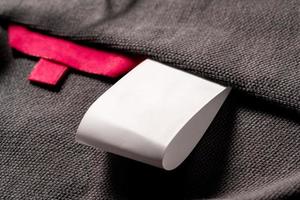 A closeup shot of a blank red fabric tag on cloth for a size label and a white tag for laundry details photo