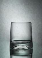 una toma vertical de un vaso vacío sobre un fondo gris foto