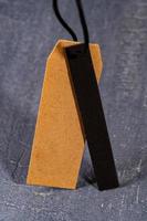 A vertical shot of a brown paper tag on a string with a thin black strip of cloth photo