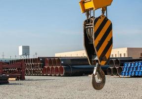 A close-up of a construction crane hook against the background of a site with oilfield pipes photo