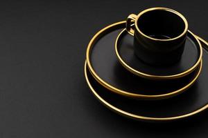 A set of black and golden ceramic plates and cup on a black background photo