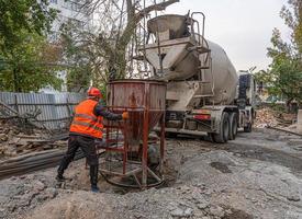 Worker on a construction site building infrastructure with machinery and tools. Pouring concrete photo