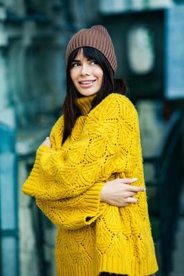 Beautiful European brunette dressed in a yellow woolen sweater and hat  outside. The beautiful girl who wears thick stylish autumn clothes in cool  weather. 12824197 Stock Photo at Vecteezy