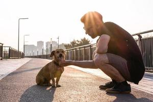 un joven apuesto camina con su perro por la mañana en una calle vacía de la ciudad. foto