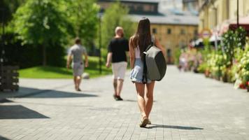 Woman walks on outdoor path carrying backpack on a sunny day video