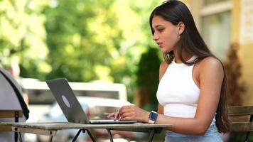 kvinna sitter på utomhus- Kafé använder sig av bärbar dator video