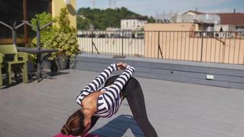 mulher se estende no tapete de ioga em um deck ao ar livre video
