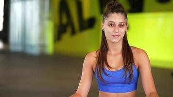 Young fit woman sits on floor of a gym video