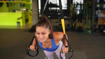 Young fit woman exercises in gym using equipment video