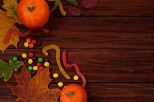 Traditional Halloween sweets. Pumpkins, autumn leaves and candies on wooden background. photo