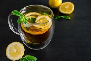 Herbal tea with lemon and mint on dark background. Delicious drink for relaxation and refreshment photo