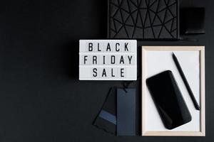 Black Friday online sale concept. Monochromatic flatlay on dark background. Smartphone and accessories. photo