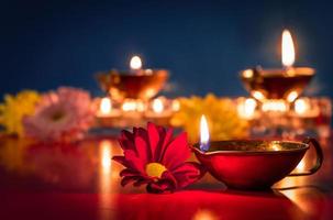 Happy Diwali. Burning diya oil lamps and flowers on blue background. Traditional Indian festival of light. photo