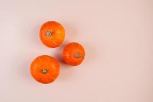 Three pumpkins on pink background. Symbol for autumn harvest, Halloween and Thanksgiving. photo