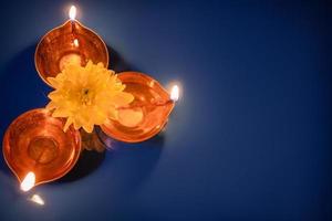 Happy Diwali. Diya oil lamps and yellow flowers on blue background. Celebrating the traditional Indian holiday of light. photo