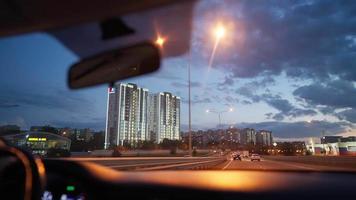 vista da janela da frente de um carro dirigindo por uma estrada movimentada iluminada por lanternas à noite. conceito de veículo e transporte. video