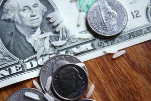 Dollar coins and dollar bills are scattered on a wooden table with grains of rice. photo