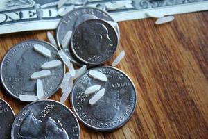 Dollar coins and dollar bills are scattered on a wooden table with grains of rice. photo