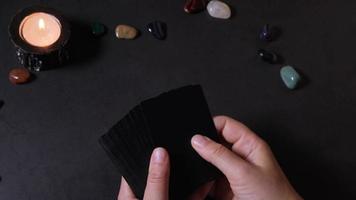 gros plan des mains d'une femme tenant et mélangeant un jeu de cartes noir. l'ésotérisme et prédire l'avenir à l'aide des cartes de tarot video