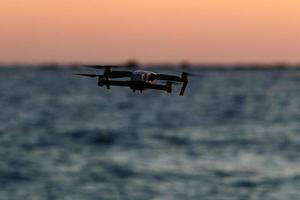 A quadrocopter with a photo camera flies over the sea.